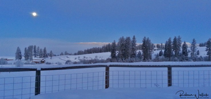 moon setting over snowy landscape