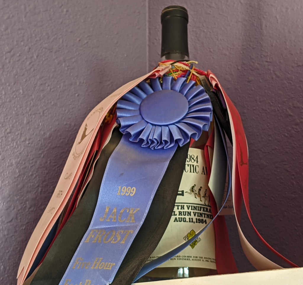 Wine bottle holding race ribbons and medals.