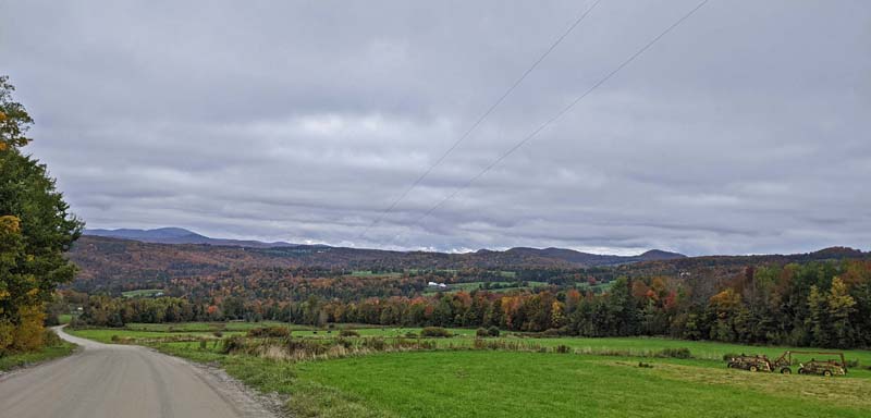 rural Vermont scenery of fields, trees, distant mountains and dirt road