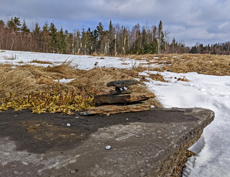 a small cairn on top of a large boulder in a field